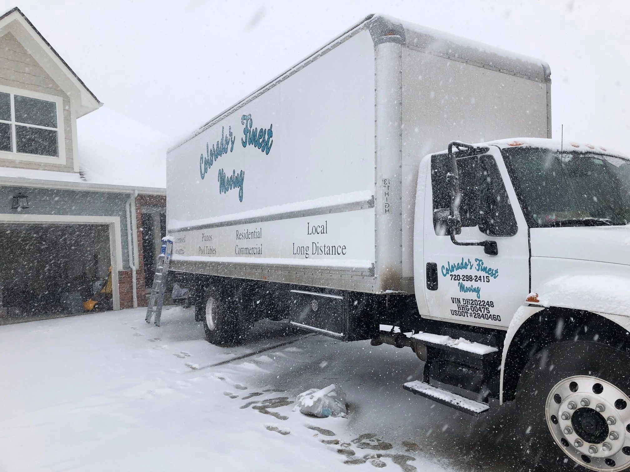 Colorado's Finest Moving truck parked in front of a home during a Colorado snowstorm